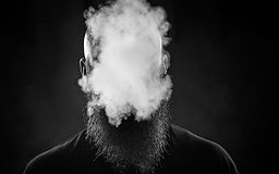 Un homme avec une barbe souffle un nuage de fumée